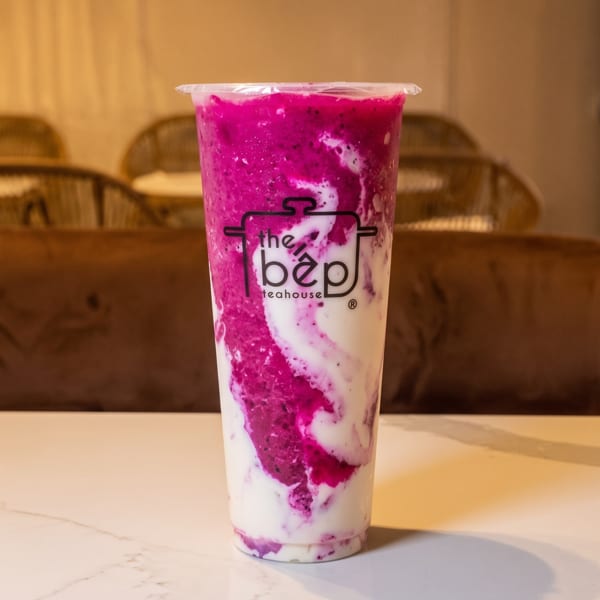 Pink and white dragon fruit smoothie from The Bep Teahouse on a white table.